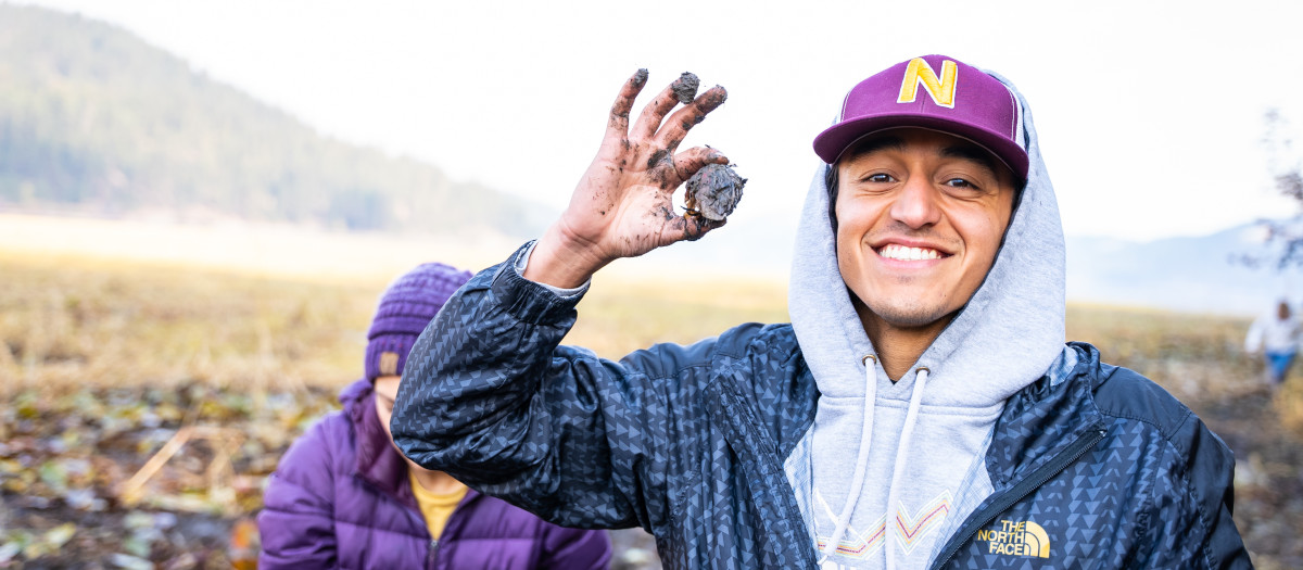 person holding a small and muddy potato