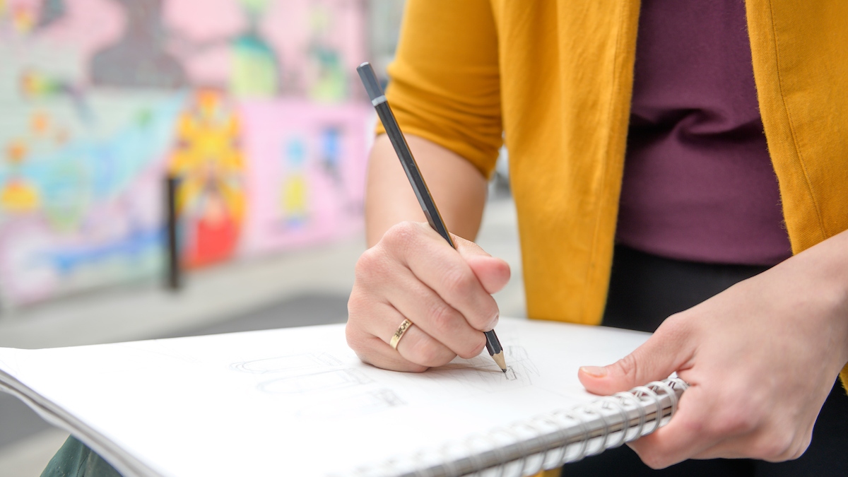 A student sketches in a notebook.