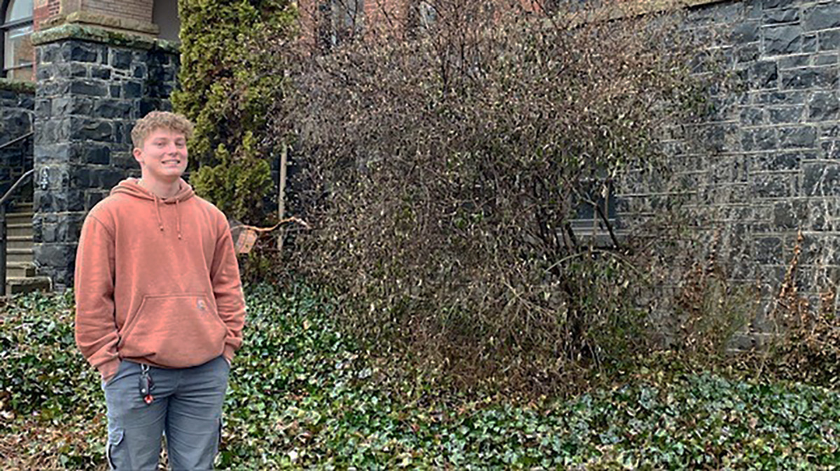 Photo of man wearing orange hoodie in front of building