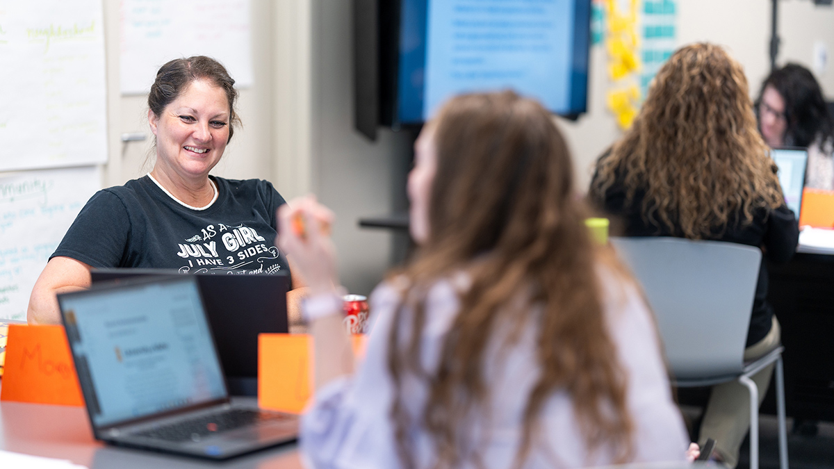 A teacher talks to a student in the classroom.