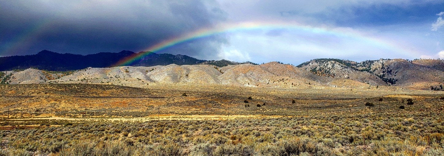 A rainbow and clouds over scrubland land